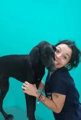 Guerreiro Negão, um cachorro preto, abraçado a uma integrante da equipe.
